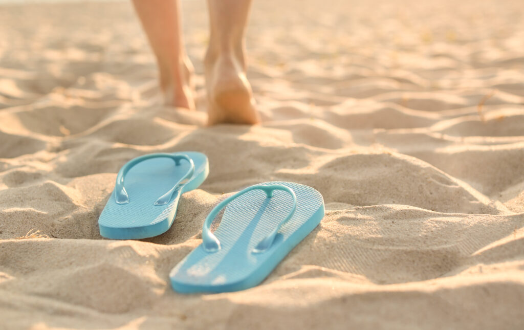 Tongues sur la plage, pieds au loins