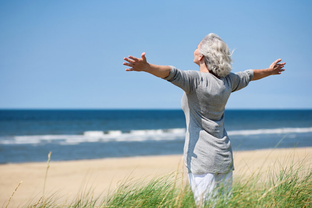 Femme ouvre les bras face à la mer