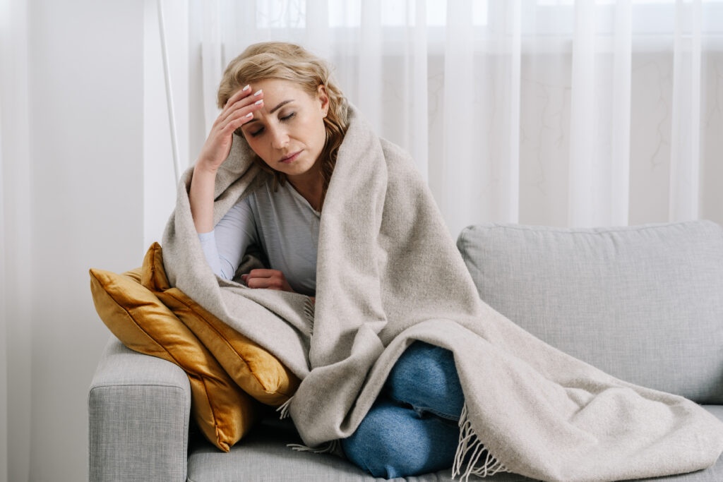 Femme sur son canapé, se tient la tête épuisée, fatiguée